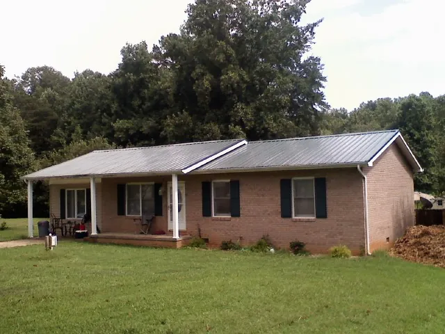 Gray metal roof on a brick ranch house with a side carport in Mandeville