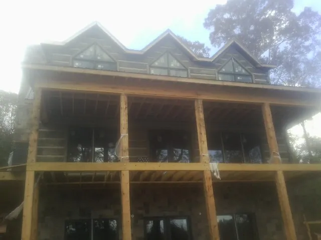 Dormers and porch framing on a large log home under construction — Roof Coating work by our crew in Mandeville