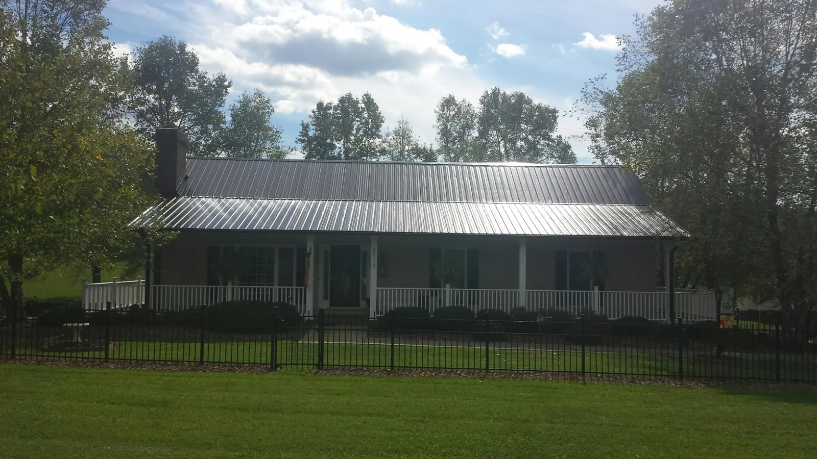 Gray metal roof on a brick ranch with a full width front porch — Gutter Guard Installation work by our crew in Mandeville
